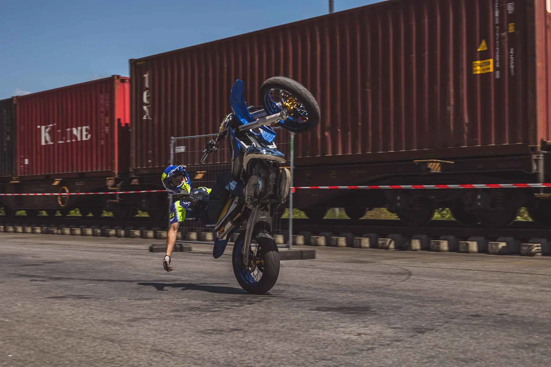 Motorradfahrer beim Handdrag vor einem Containerzug