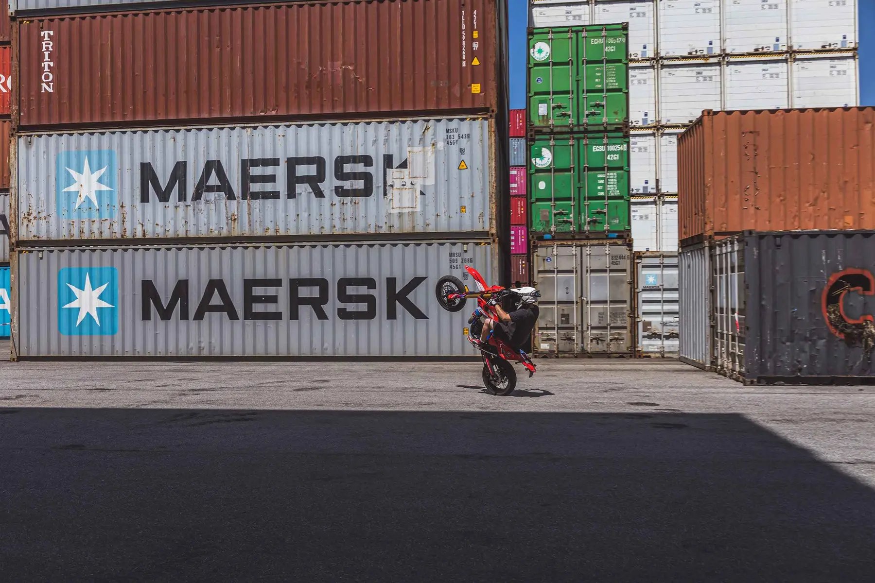 Motorradfahrer beim Wheelie zwischen gestapelten Containern im Nürnberger Containerhafen